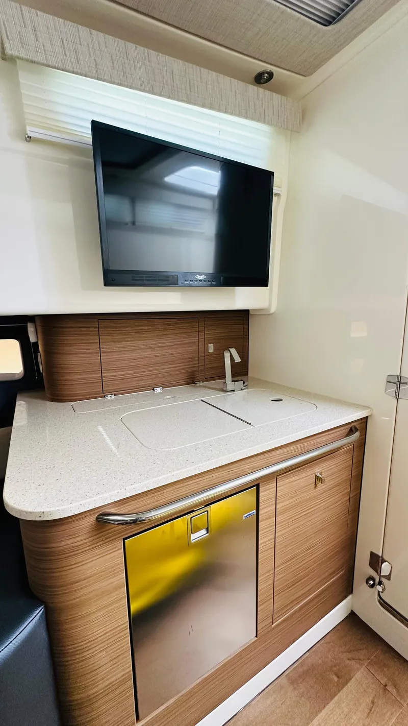 Slide: The Image of 2021 Boston Whaler 420 Outrage interior with modern kitchenette and mounted TV. - 19