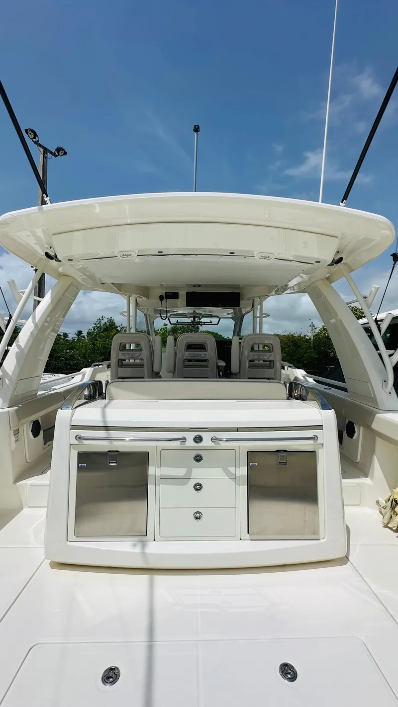 Slide: The Image of Boston Whaler 420 Outrage 2021 boat interior with seating and storage, under clear blue sky. - 6
