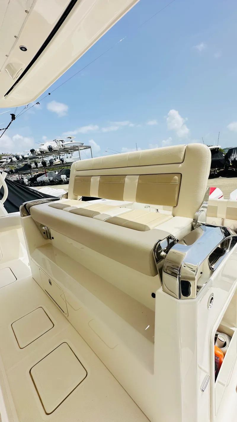 Slide: The Image of 2021 Boston Whaler 420 Outrage boat interior with beige seating and chrome accents under a clear sky. - 8