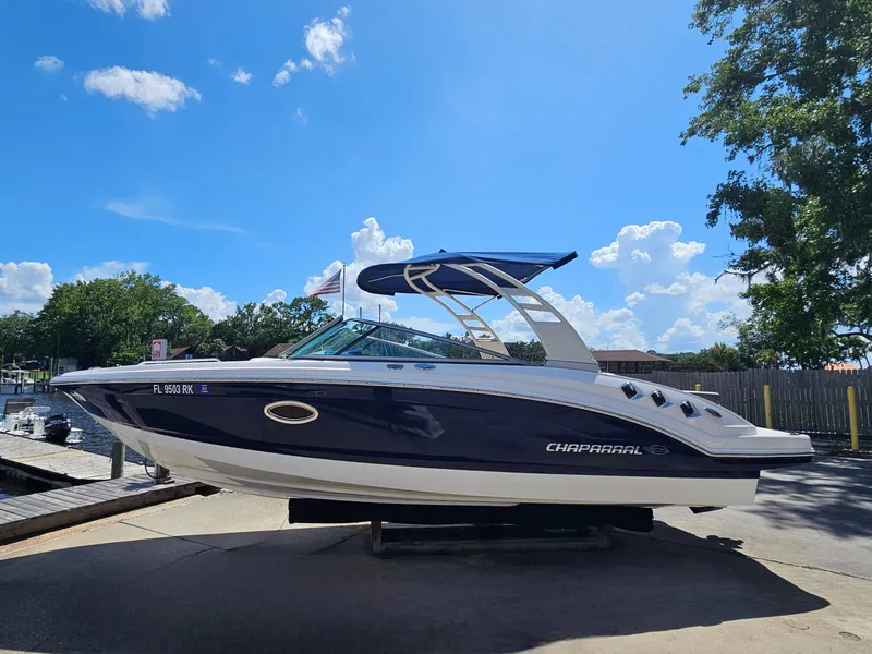 Slide: The Image of 2017 Chaparral 246 SSi boat with blue hull and canopy, docked under a clear sky. - 13