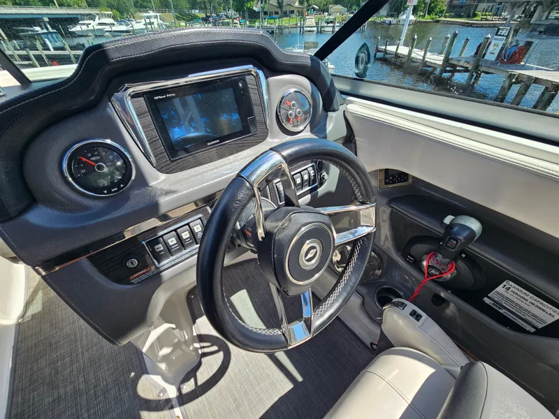 Slide: The Image of 2017 Chaparral 246 SSi boat dashboard with steering wheel and controls, dockside view. - 19