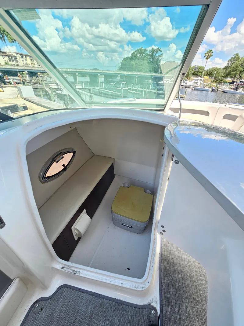 Slide: The Image of 2017 Chaparral 246 SSi boat interior with seating and storage, under a clear blue sky. - 28