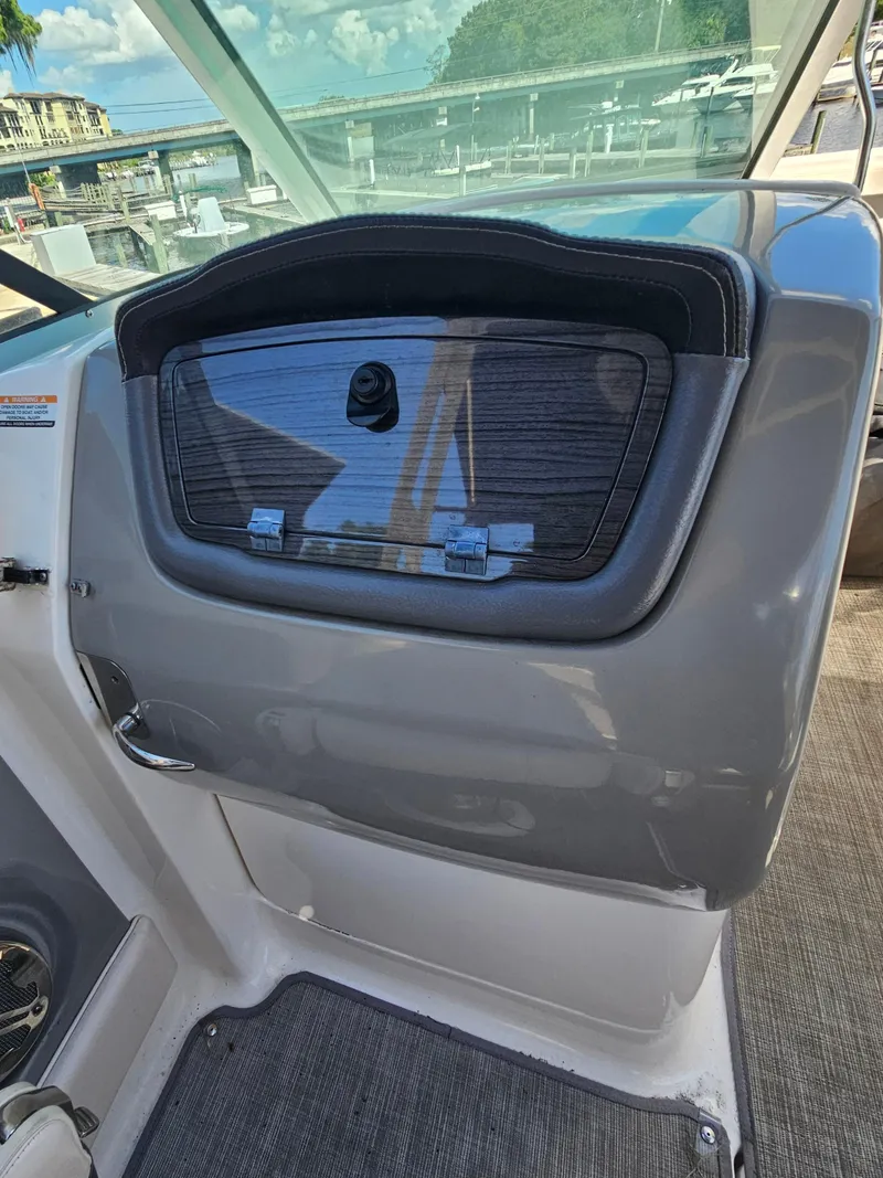 Slide: The Image of 2017 Chaparral 246 SSi boat dashboard with storage compartment, docked near marina. - 29