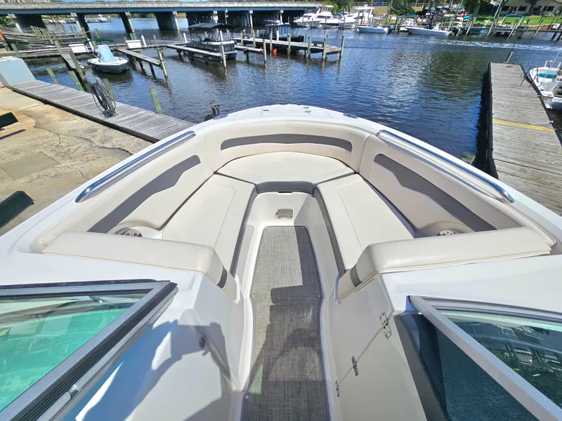 Slide: The Image of 2017 Chaparral 246 SSi boat interior with spacious seating, docked by a scenic waterfront. - 30