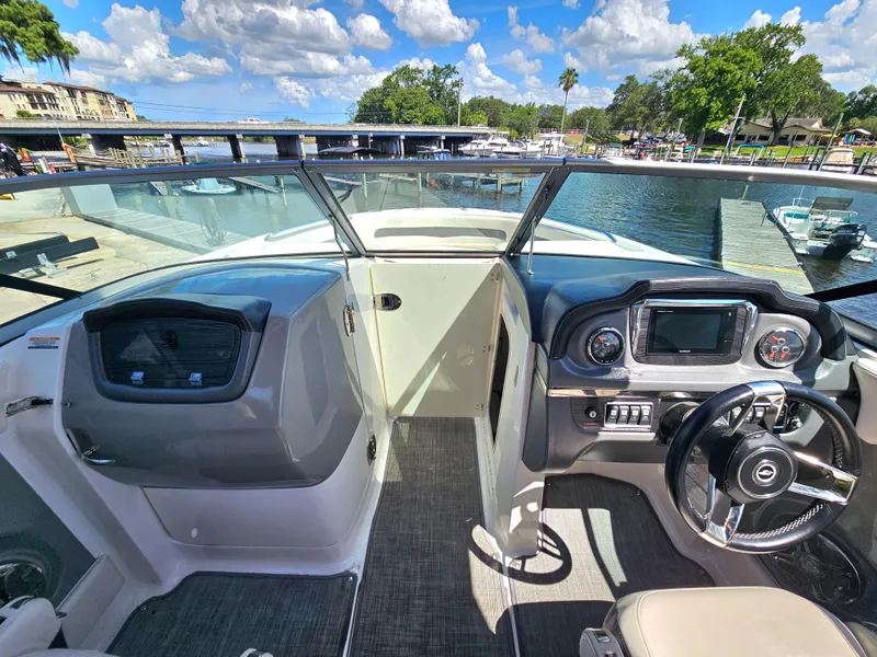 Slide: The Image of 2017 Chaparral 246 SSi boat cockpit with steering wheel and dashboard, docked by a scenic waterfront. - 32