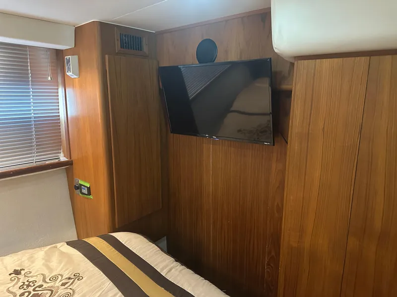 Slide: The Image of 1993 Carver 350 Aft Cabin interior with wood paneling and mounted TV. - 15