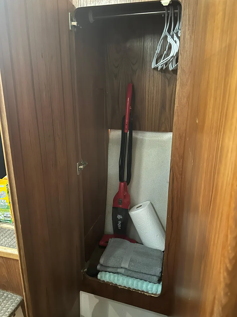 Slide: The Image of 1993 Carver 350 Aft Cabin closet with vacuum, hangers, towels, and paper towels. - 21
