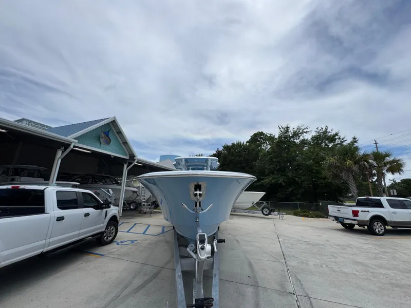 Slide: The Image of 2026 Invincible 43 Open Fisherman boat on trailer, parked near trucks and trees. - 6