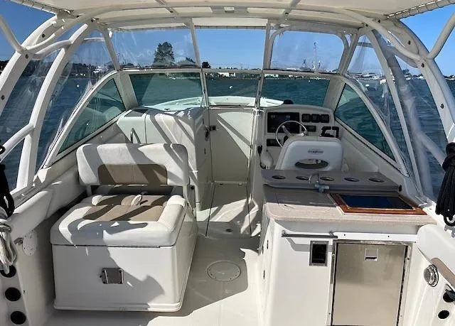 Slide: The Image of 2015 Sailfish 275 DC boat interior with seating, helm, and kitchenette on a sunny day. - 10