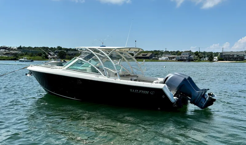 Slide: The Image of 2015 Sailfish 275 DC boat on water, clear sky, coastal background. - 2