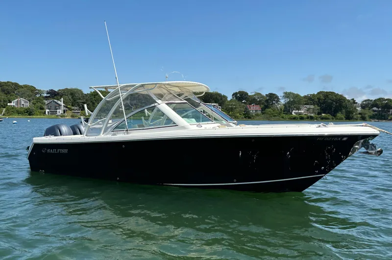 Slide: The Image of 2015 Sailfish 275 DC boat on water, clear sky, shoreline in background. - 3