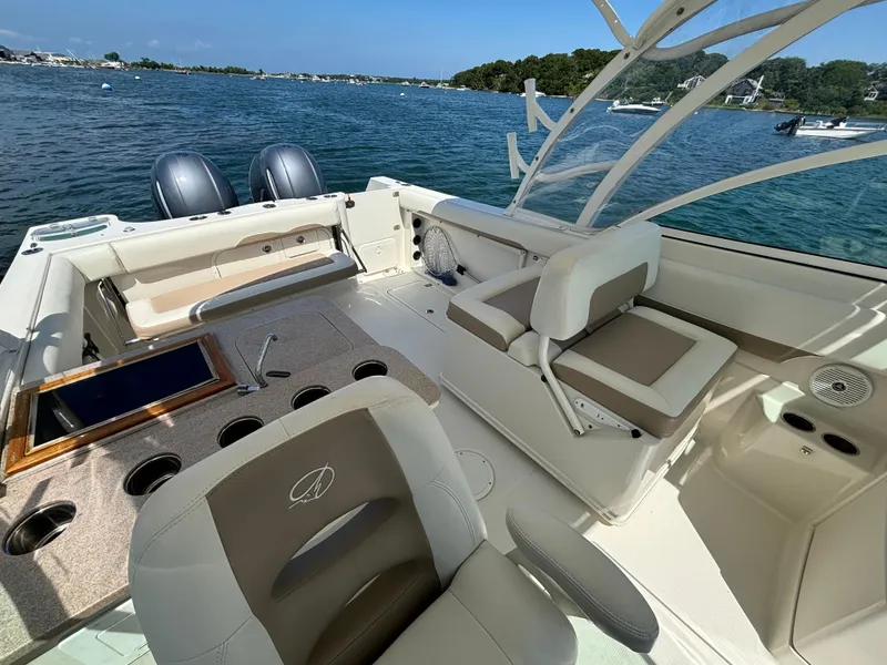 Slide: The Image of 2015 Sailfish 275 DC boat interior with seating, cup holders, and dual engines on a sunny day. - 9