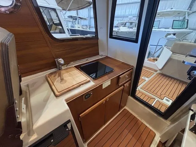 Slide: The Image of Interior of 2025 Ranger Tugs R-23 boat with wooden cabinetry and compact kitchen area. - 10