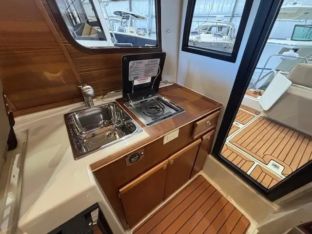 Slide: The Image of 2025 Ranger Tugs R-23 boat interior with kitchenette, sink, and stove. - 11