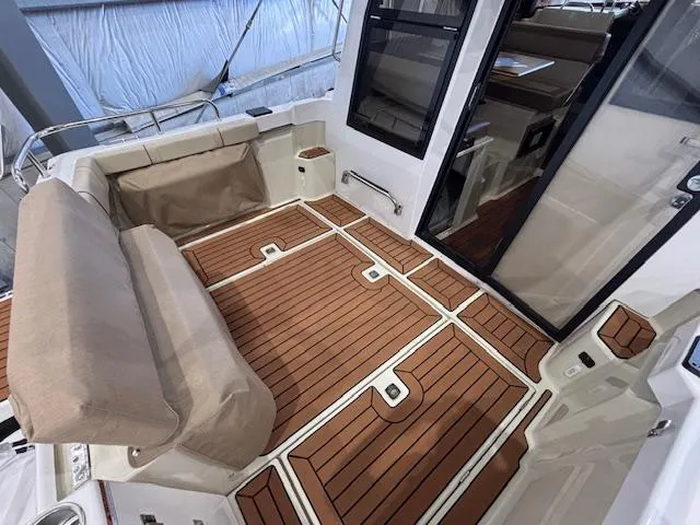 Slide: The Image of 2025 Ranger Tugs R-23 boat interior with teak flooring and cushioned seating. - 13