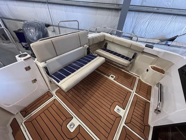 Slide: The Image of 2025 Ranger Tugs R-23 boat interior with cushioned seating and wood-patterned flooring. - 14