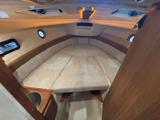 Slide: The Image of 2025 Ranger Tugs R-23 cabin interior with cozy seating and wooden accents. - 4