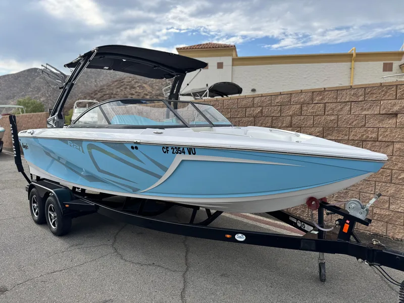 Slide: The Image of 2019 Tigé R21 boat in light blue on a trailer, parked outdoors. - 1
