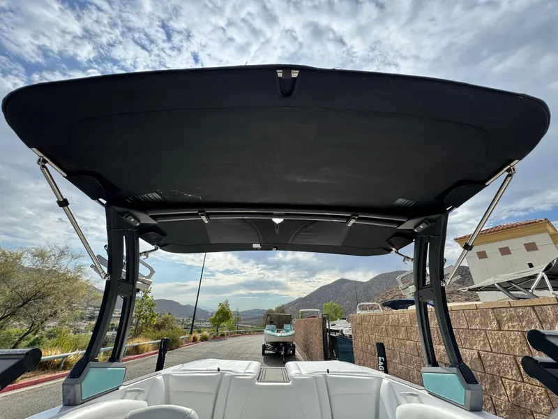 Slide: The Image of 2019 Tigé R21 boat with black canopy, white interior, and scenic mountain backdrop. - 12