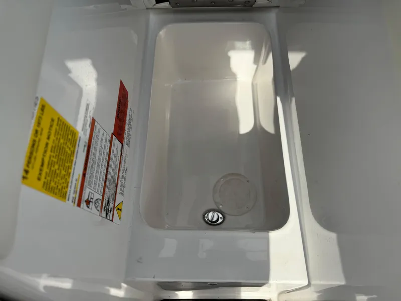 Slide: The Image of 2019 Tigé R21 boat storage compartment with safety labels and drain plug. - 19