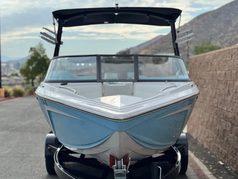 Slide: The Image of 2019 Tigé R21 boat on trailer, parked near mountains and brick wall. - 2