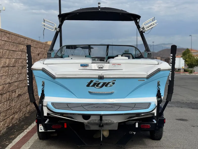 Slide: The Image of 2019 Tigé R21 boat, blue and white, parked on a trailer, rear view. - 4
