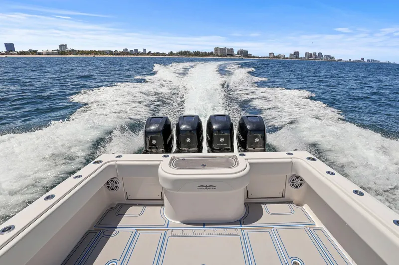 Slide: The Image of 2013 Invincible 42 Open Fisherman boat cruising on open water with city skyline. - 15
