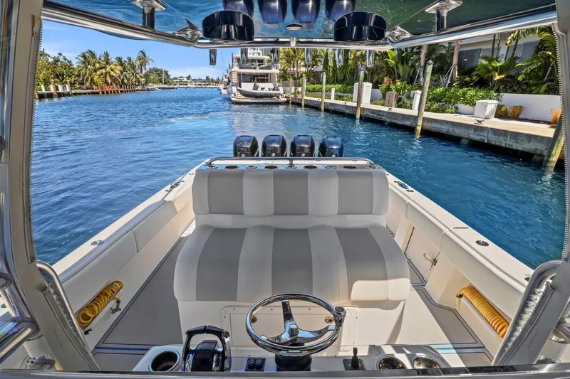 Slide: The Image of 2013 Invincible 42 Open Fisherman boat on a sunny waterfront, featuring sleek seating and controls. - 21