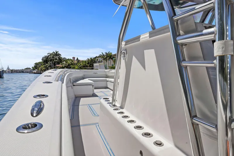Slide: The Image of 2013 Invincible 42 Open Fisherman boat with sleek design, docked near palm trees. - 27