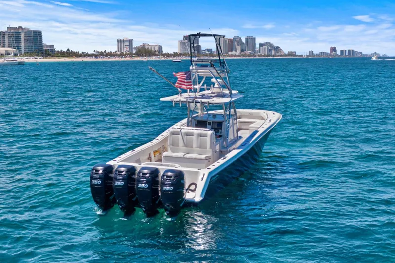 Slide: The Image of 2013 Invincible 42 Open Fisherman boat with four engines on blue ocean near city skyline. - 3