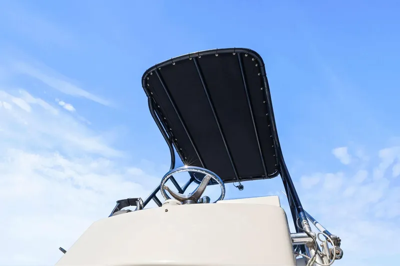 Slide: The Image of 2013 Invincible 42 Open Fisherman boat helm with T-top against blue sky. - 37
