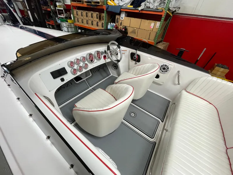 Slide: The Image of 2022 Donzi 22 Classic boat interior with white seats and red trim, showcasing dashboard and controls. - 14