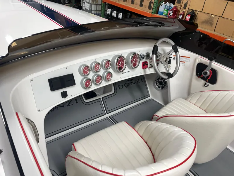 Slide: The Image of 2022 Donzi 22 Classic boat interior with white seats and red-trimmed dashboard. - 16