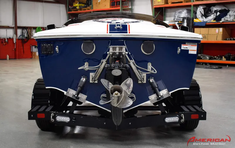 Slide: The Image of 2022 Donzi 22 Classic boat rear view in a garage, showcasing propeller and trim tabs. - 5