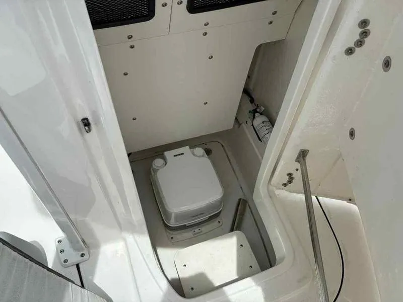 Slide: The Image of 2024 Robalo 246 Cayman boat interior with portable toilet and storage compartment. - 27