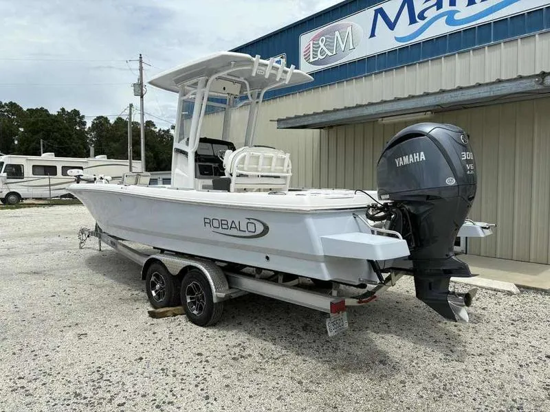 Slide: The Image of 2024 Robalo 246 Cayman boat with Yamaha engine on trailer, parked outside a marine shop. - 4