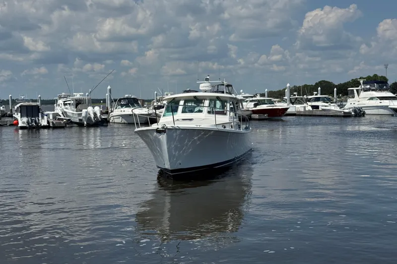 Slide: The Image of 2022 Back Cove 34O boat cruising in a marina under a cloudy sky. - 10