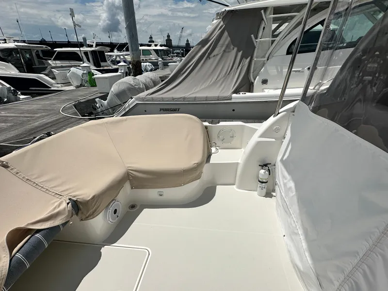 Slide: The Image of Back Cove 34O 2022 yacht deck with beige seating, docked among other boats. - 28