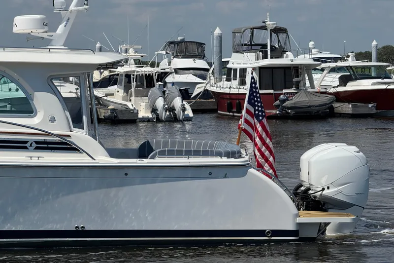Slide: The Image of 2022 Back Cove 34O yacht with American flag in a marina setting. - 3