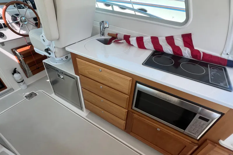 Slide: The Image of 2022 Back Cove 34O yacht interior with kitchenette, featuring stove, microwave, and sink. - 32
