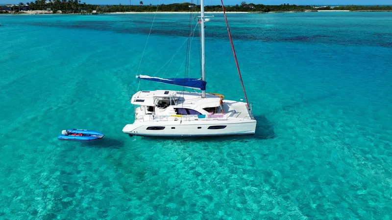 The Image of Catamaran Leopard 44 sailing in clear turquoise waters, 2013 model, with a small blue dinghy nearby. - 0