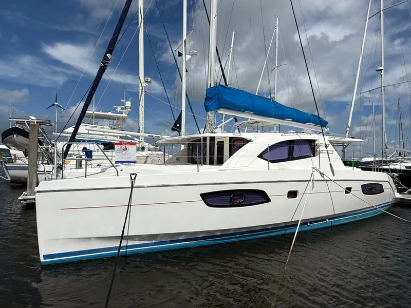 Slide: The Image of 2013 Leopard 44 catamaran docked at marina, featuring blue sail cover. - 2