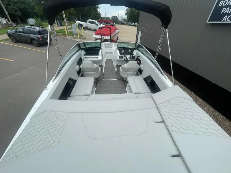 Slide: The Image of 2025 Four Winns H4 Freedom boat interior with seating and steering wheel, parked outdoors. - 4