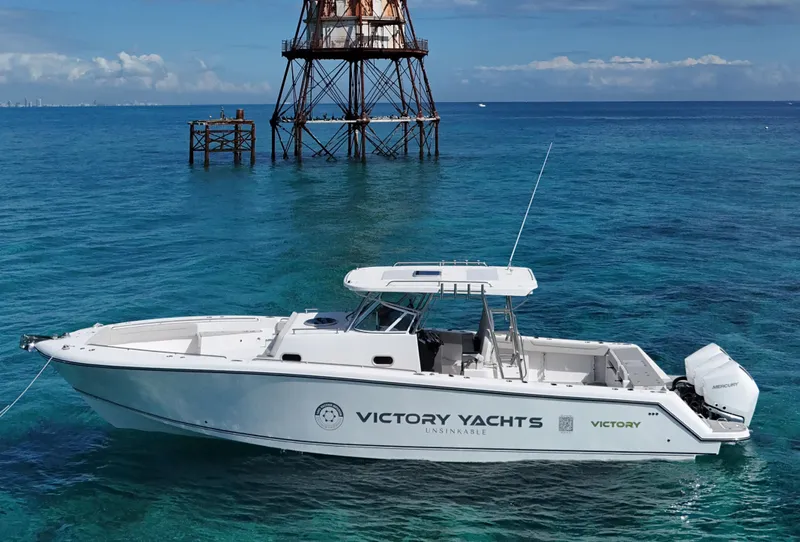 Slide: The Image of 2024 Victory V400 Open Sea yacht on clear blue water near a metal structure. - 2