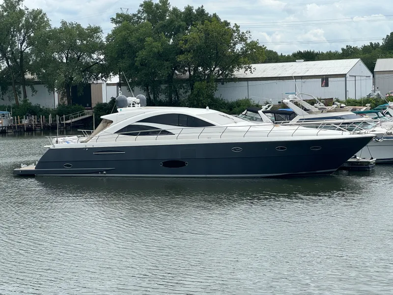 Slide: The Image of 2007 Uniesse 70 Sport yacht docked on calm water, surrounded by trees and buildings. - 2