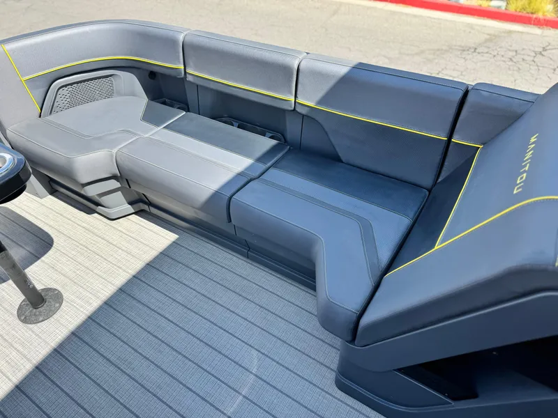 Slide: The Image of 2024 Manitou Explore 24 Navigator boat seating with sleek design and yellow accents. - 11