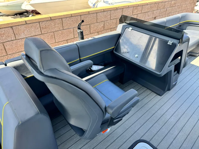 Slide: The Image of 2024 Manitou Explore 24 Navigator boat interior with sleek seating and modern dashboard. - 21