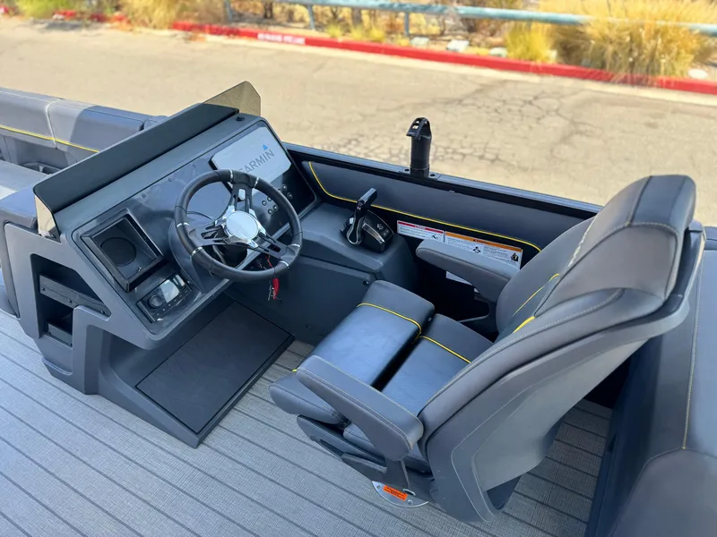 Slide: The Image of 2024 Manitou Explore 24 Navigator boat cockpit with steering wheel and seating. - 24