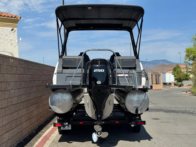 Slide: The Image of 2024 Manitou Explore 24 Navigator pontoon boat with powerful 250 HP engine, parked outdoors. - 5