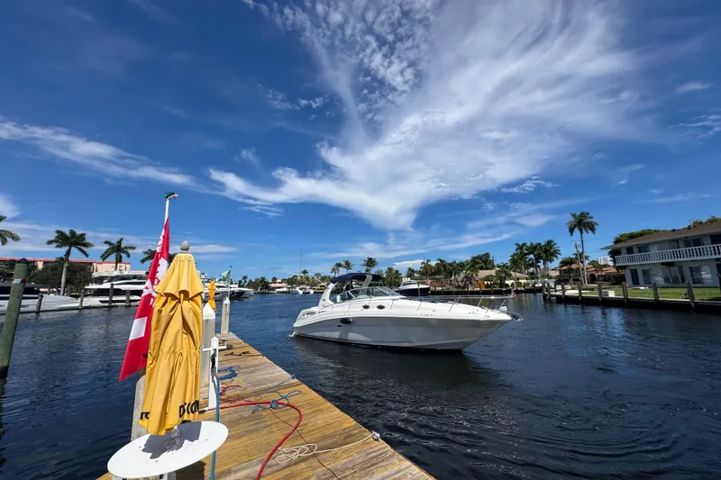 Slide: The Image of 2004 Sea Ray 340 Sundancer interior with beige seating, wooden cabinets, and compact dining area. - 27